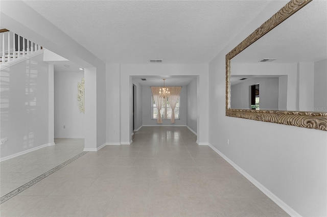 hall featuring a chandelier, light tile patterned floors, and a textured ceiling