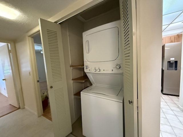 washroom with stacked washer and dryer and light tile patterned flooring