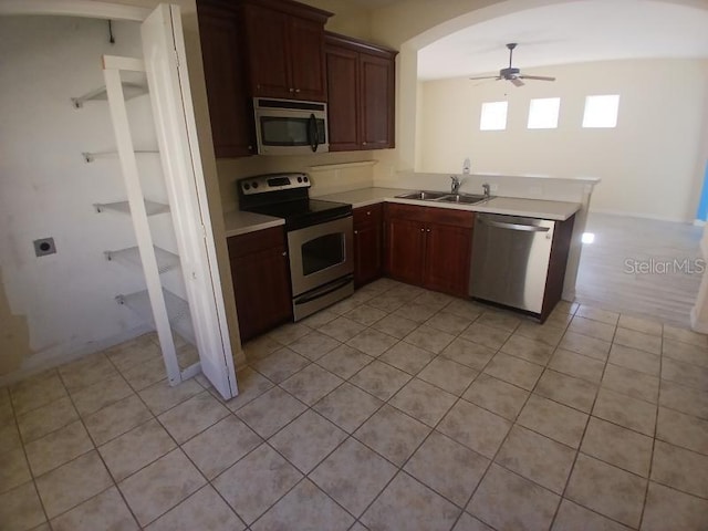 kitchen with ceiling fan, sink, kitchen peninsula, light tile patterned floors, and appliances with stainless steel finishes