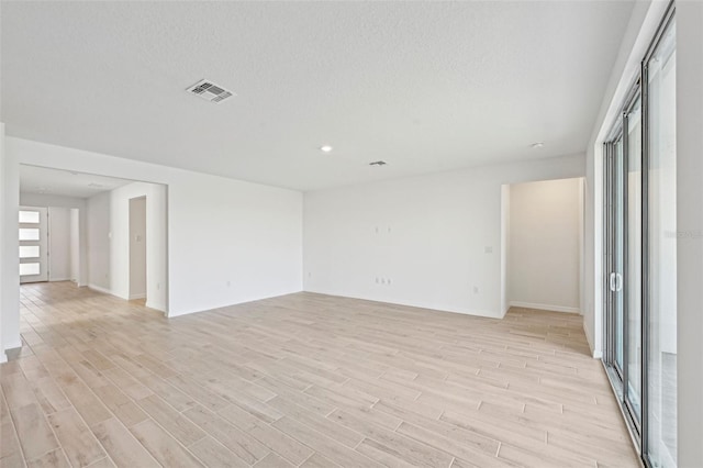 empty room featuring light wood-type flooring and a textured ceiling