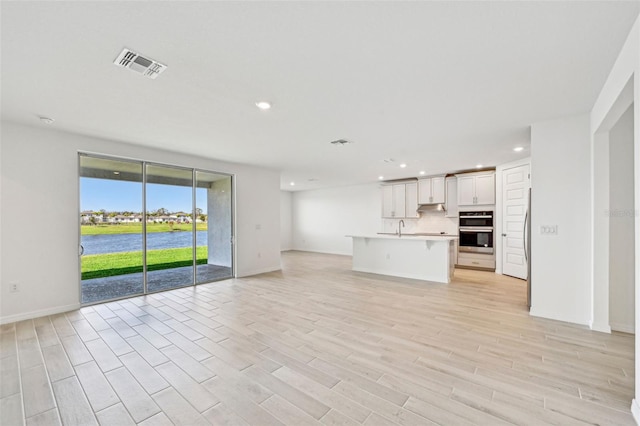 unfurnished living room with sink and light hardwood / wood-style flooring