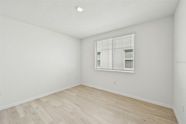 unfurnished room featuring a textured ceiling and light hardwood / wood-style floors