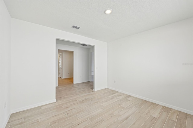 unfurnished room featuring light wood-type flooring and a textured ceiling