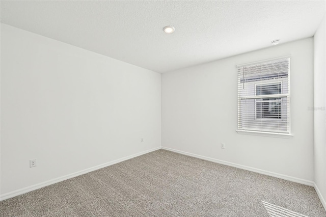 carpeted empty room featuring a textured ceiling