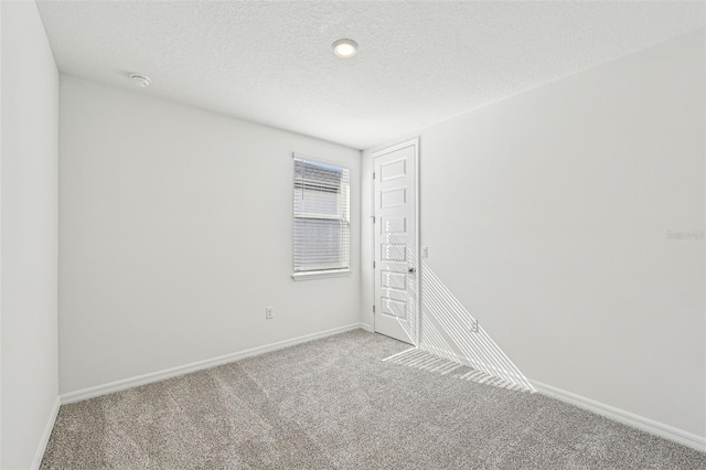 empty room with light colored carpet and a textured ceiling