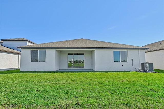 rear view of property with central AC unit and a lawn