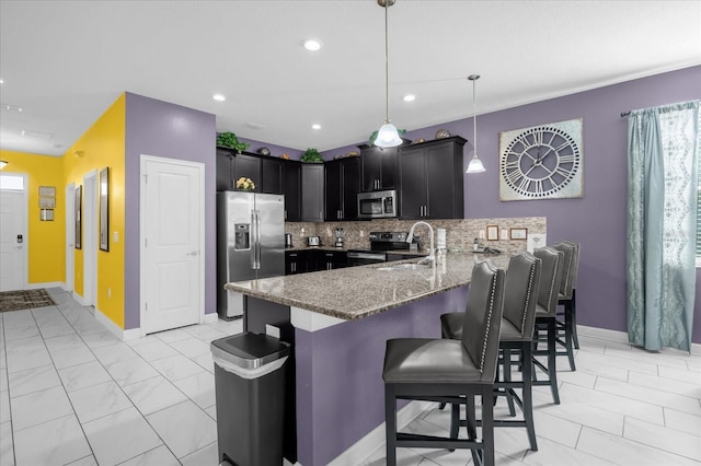 kitchen with tasteful backsplash, kitchen peninsula, decorative light fixtures, a breakfast bar, and appliances with stainless steel finishes