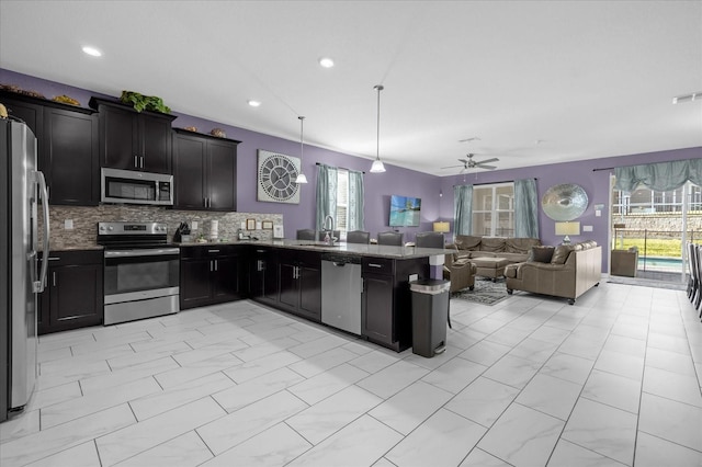 kitchen with sink, ceiling fan, tasteful backsplash, decorative light fixtures, and stainless steel appliances