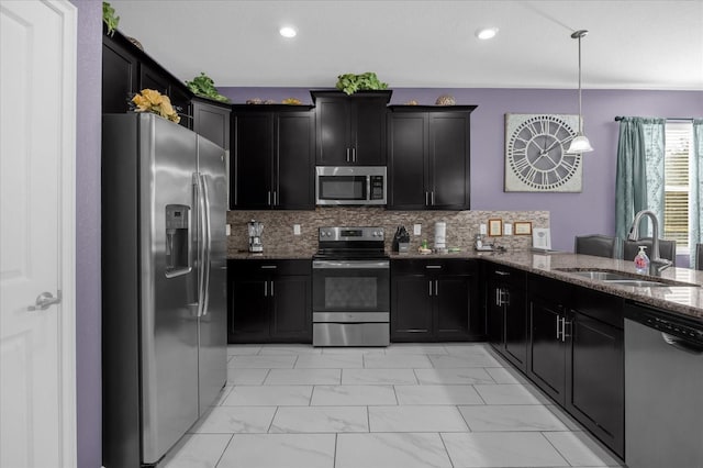 kitchen featuring sink, pendant lighting, stone countertops, decorative backsplash, and appliances with stainless steel finishes