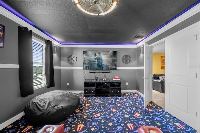 home theater room featuring a textured ceiling, carpet floors, and ornamental molding