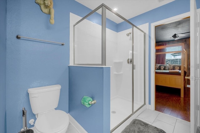 bathroom featuring hardwood / wood-style floors, toilet, ceiling fan, and an enclosed shower