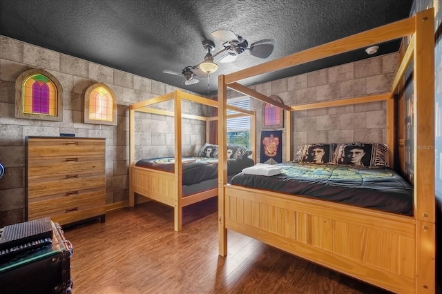 bedroom featuring wood-type flooring, a textured ceiling, and ceiling fan