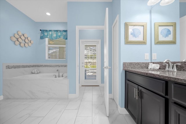 bathroom with vanity and tiled tub