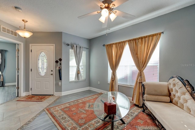 tiled foyer featuring a textured ceiling and ceiling fan