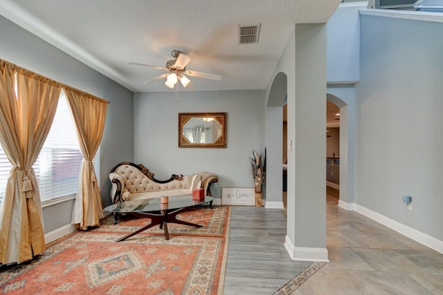 living area featuring ceiling fan and a textured ceiling