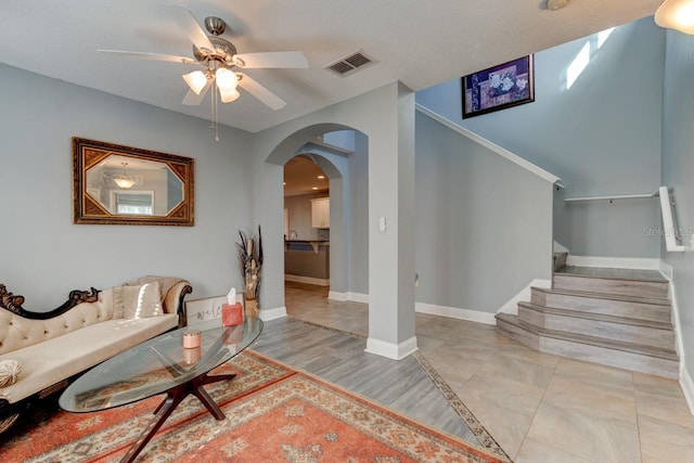 living room featuring a textured ceiling, light wood-type flooring, and ceiling fan