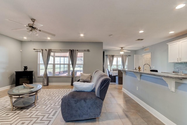 tiled living room with a wealth of natural light and ceiling fan