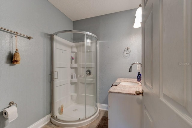 bathroom featuring vanity, an enclosed shower, and a textured ceiling