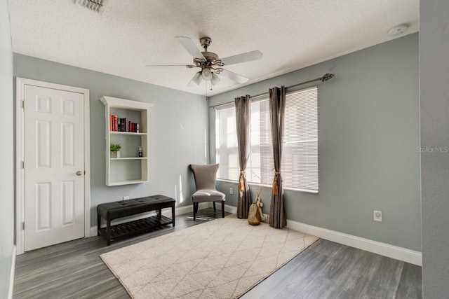 sitting room with ceiling fan, wood-type flooring, and a textured ceiling