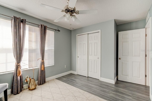 bedroom with ceiling fan, light hardwood / wood-style floors, a closet, and multiple windows