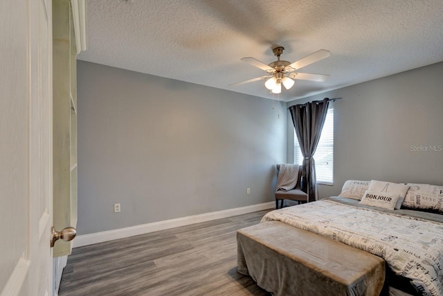 bedroom with ceiling fan, wood-type flooring, and a textured ceiling