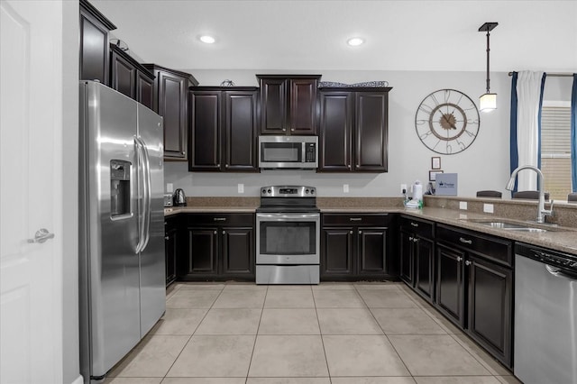 kitchen featuring light stone countertops, appliances with stainless steel finishes, sink, decorative light fixtures, and light tile patterned flooring