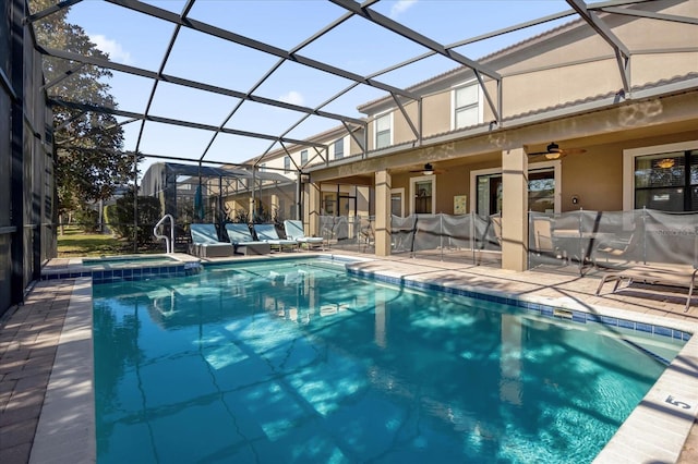 view of swimming pool featuring glass enclosure, ceiling fan, and a patio