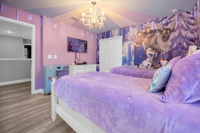 bedroom with wood-type flooring, an inviting chandelier, and a closet