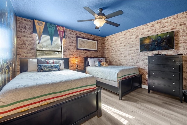 bedroom with ceiling fan, wood-type flooring, and a textured ceiling