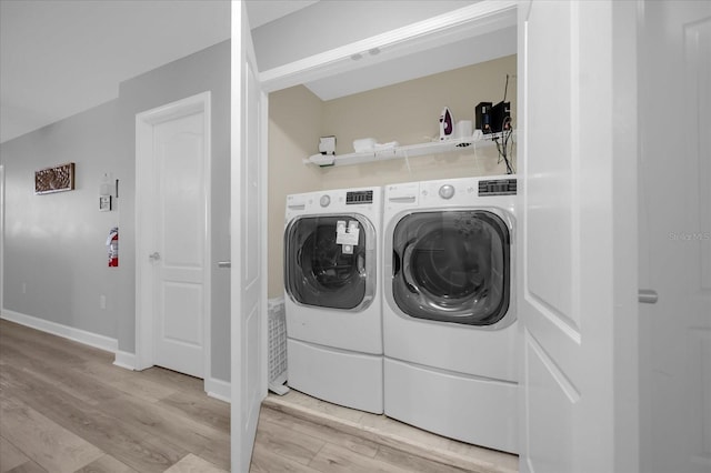 laundry area with light wood-type flooring and washing machine and clothes dryer