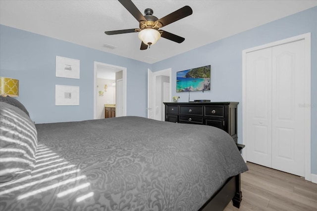 bedroom with ensuite bath, ceiling fan, a closet, and wood-type flooring