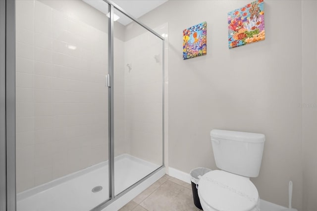 bathroom featuring tile patterned flooring, toilet, and a shower with shower door