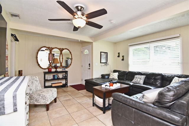 living room with ceiling fan, light tile patterned flooring, and a textured ceiling