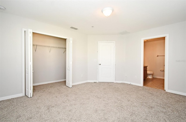 unfurnished bedroom featuring connected bathroom, light colored carpet, and a closet