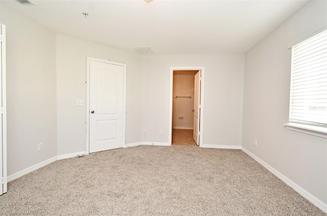 unfurnished bedroom with multiple windows, light carpet, and a closet