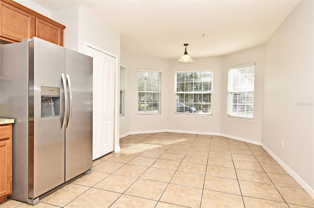 kitchen featuring stainless steel refrigerator with ice dispenser, light tile patterned floors, and hanging light fixtures