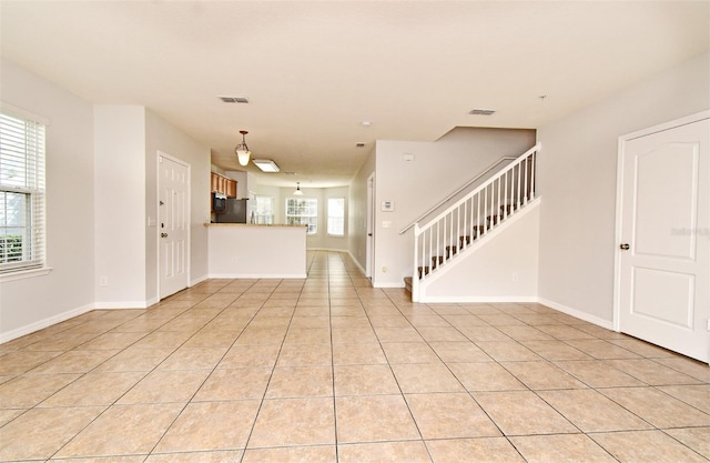 unfurnished living room with light tile patterned flooring and a healthy amount of sunlight