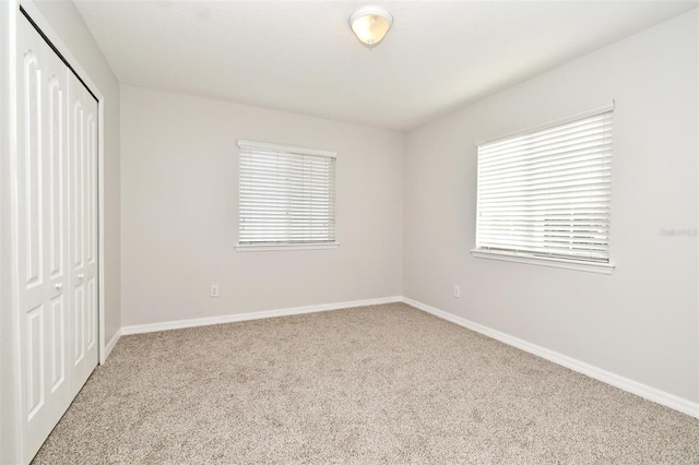 unfurnished bedroom featuring a closet and light colored carpet