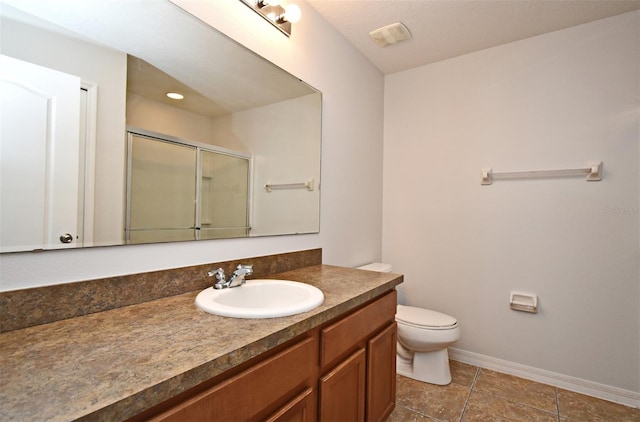 bathroom featuring tile patterned floors, vanity, toilet, and a shower with door