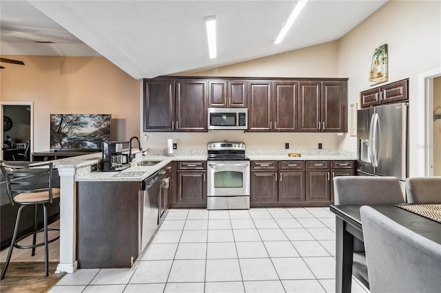 kitchen with lofted ceiling, sink, light tile patterned floors, kitchen peninsula, and stainless steel appliances