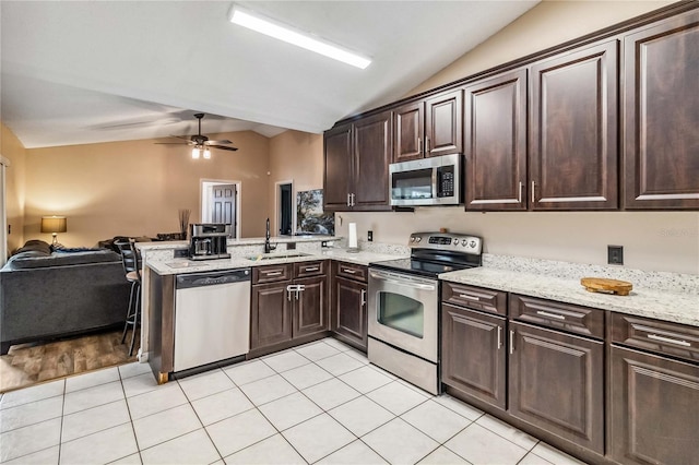 kitchen featuring sink, light tile patterned floors, stainless steel appliances, and vaulted ceiling