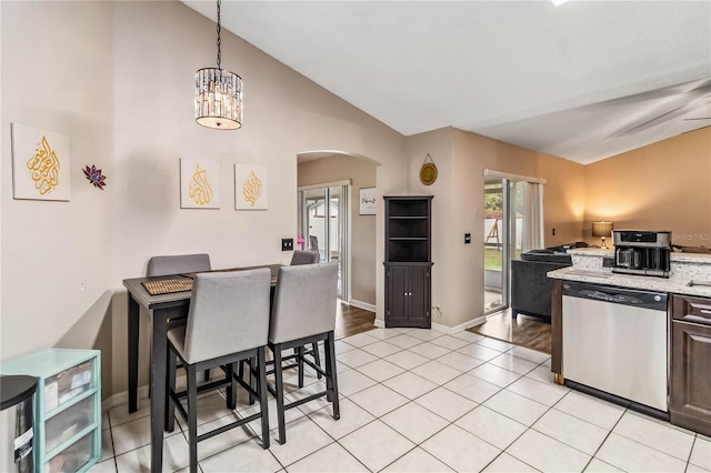 kitchen featuring dishwasher, lofted ceiling, light tile patterned floors, decorative light fixtures, and light stone counters