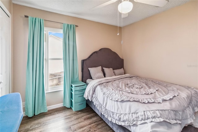 bedroom featuring multiple windows, hardwood / wood-style floors, a textured ceiling, and ceiling fan