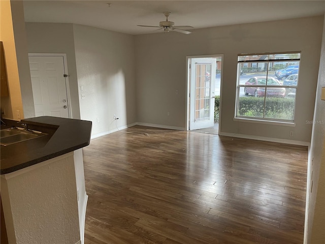 unfurnished living room featuring ceiling fan, sink, and dark wood-type flooring