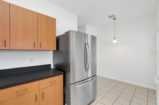 kitchen featuring light tile patterned floors, hanging light fixtures, and stainless steel refrigerator