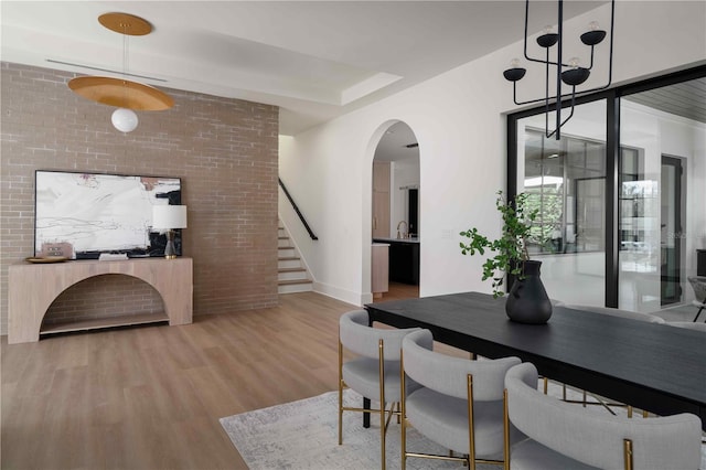 dining area featuring sink, brick wall, and hardwood / wood-style flooring