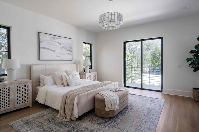 bedroom featuring access to exterior, hardwood / wood-style flooring, and a chandelier