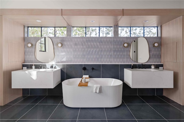 bathroom featuring a tub, tile patterned flooring, vanity, and tile walls