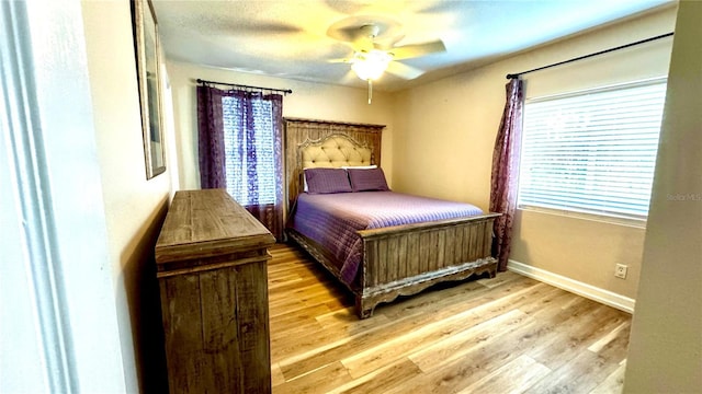 bedroom with multiple windows, ceiling fan, and light hardwood / wood-style floors