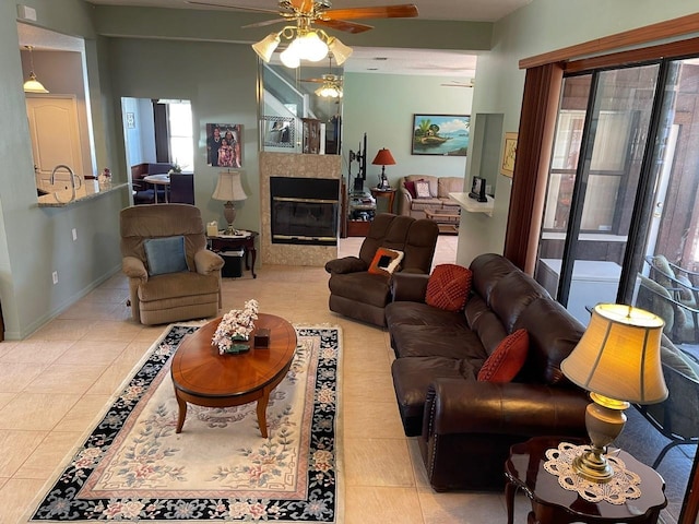 living area with a tiled fireplace, tile patterned flooring, a ceiling fan, and baseboards